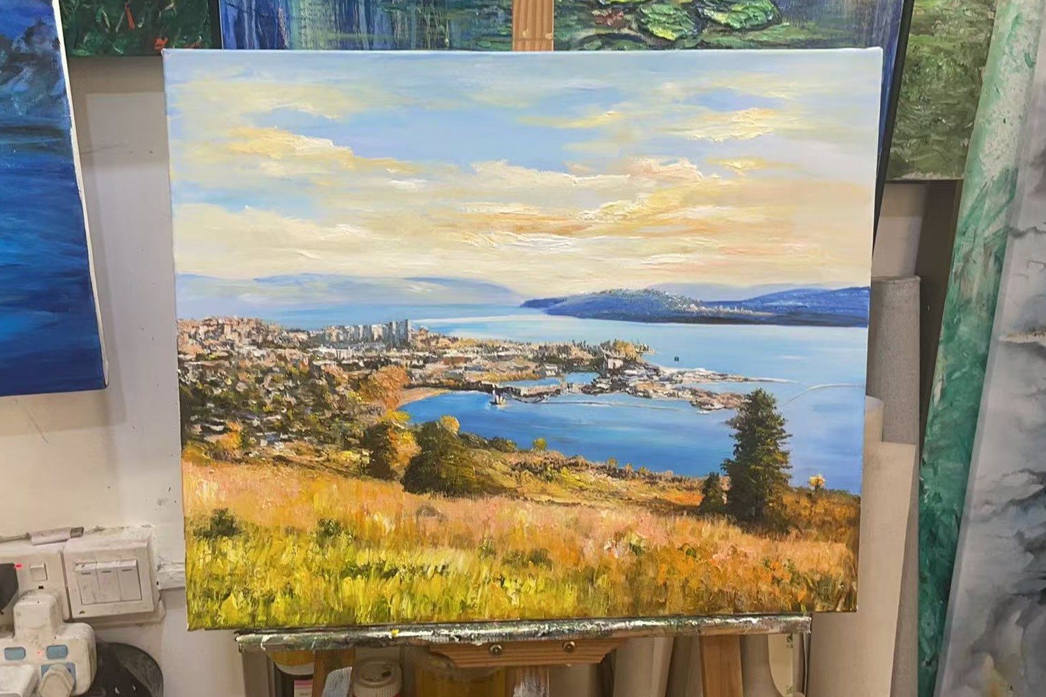 Phone photo of the Knox Mountain painting on an easel, with other canvases around it